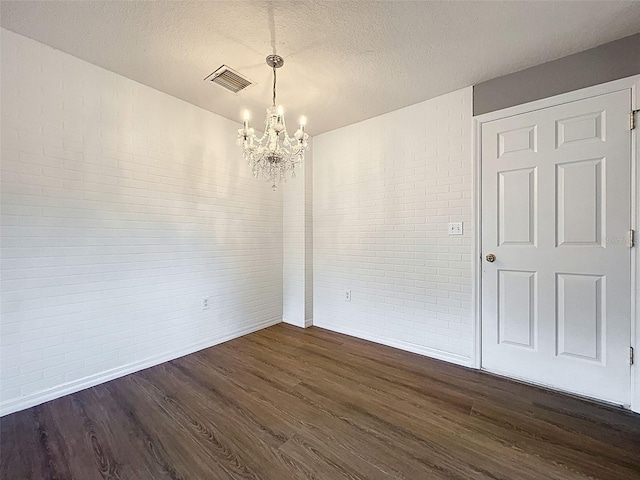 12214 Partridge Hill Row, Hudson, FL 34667 - empty room featuring brick wall, a chandelier, dark wood finished floors, and a textured ceiling