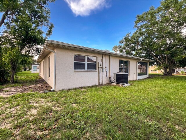 12214 Partridge Hill Row, Hudson, FL 34667 - back of house featuring stucco siding and a lawn