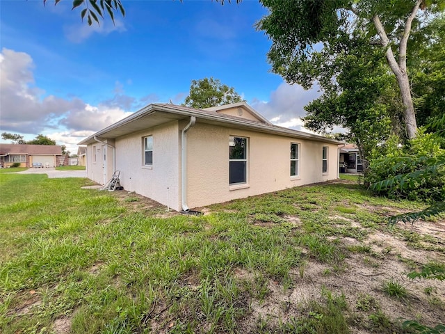 12214 Partridge Hill Row, Hudson, FL 34667 - view of side of property with stucco siding and a lawn
