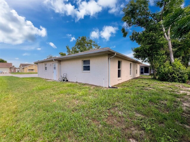 12214 Partridge Hill Row, Hudson, FL 34667 - back of house featuring stucco siding and a lawn