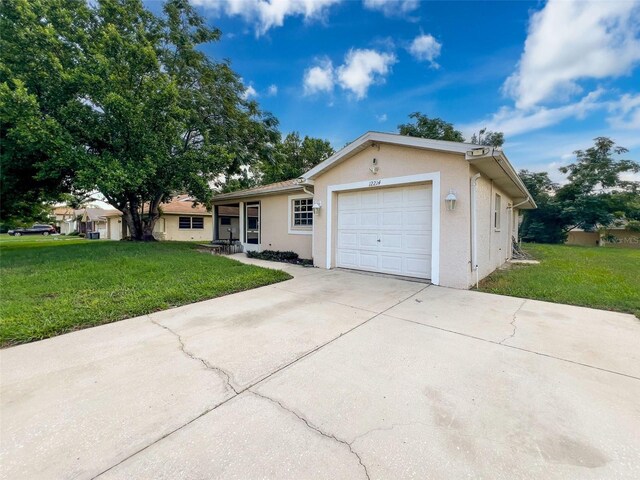 12214 Partridge Hill Row, Hudson, FL 34667 - ranch-style home featuring a front yard, a garage, stucco siding, and concrete driveway