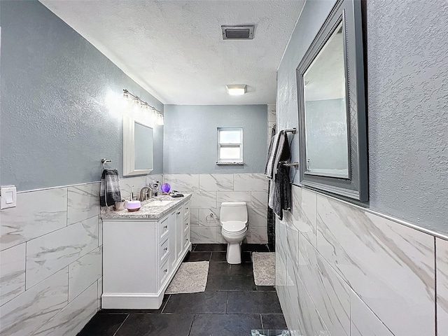 8640 Horizon Ln, Hudson, FL 34667 - bathroom featuring tile walls, a textured wall, a textured ceiling, wainscoting, and tile patterned floors