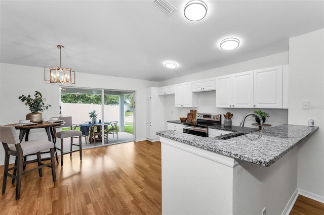 11619 Crest Creek Dr, Riverview, FL 33569 - kitchen featuring stainless steel electric range, light stone countertops, light wood-style flooring, white cabinets, and a peninsula