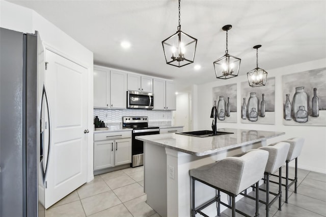 11861 Downy Birch Dr, Riverview, FL 33569 - kitchen with appliances with stainless steel finishes, light tile patterned floors, backsplash, an island with sink, and light stone countertops