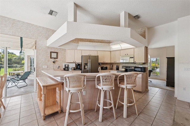8921 Kilmer Way, Hudson, FL 34667 - kitchen featuring appliances with stainless steel finishes, light tile patterned flooring, a peninsula, a breakfast bar, and light countertops