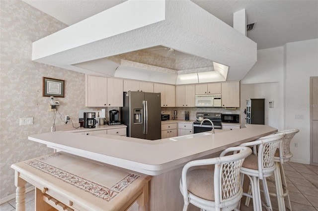 8921 Kilmer Way, Hudson, FL 34667 - kitchen featuring black appliances, light countertops, wallpapered walls, a kitchen breakfast bar, and light tile patterned floors