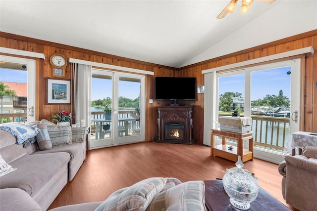 13825 San Juan Ave, Hudson, FL 34667 - living area featuring wooden walls, lofted ceiling, a lit fireplace, wood finished floors, and ceiling fan