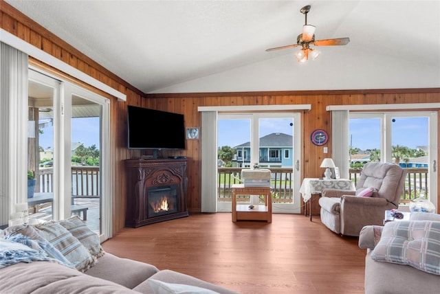13825 San Juan Ave, Hudson, FL 34667 - living area with vaulted ceiling, wood walls, healthy amount of natural light, a glass covered fireplace, and a ceiling fan