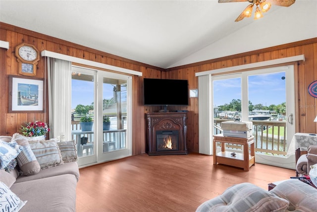 13825 San Juan Ave, Hudson, FL 34667 - living area featuring wood walls, lofted ceiling, a glass covered fireplace, a ceiling fan, and light wood-type flooring