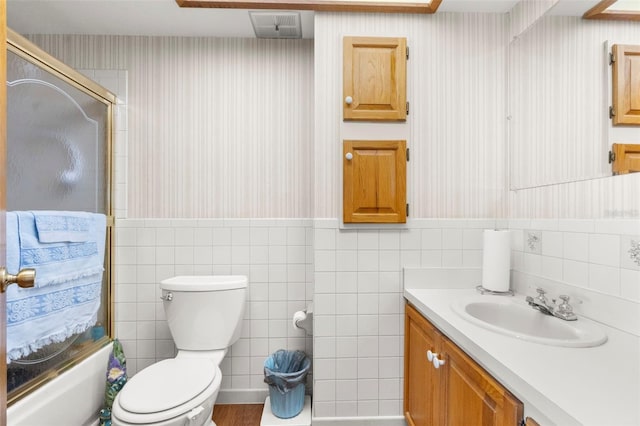 13825 San Juan Ave, Hudson, FL 34667 - full bath featuring tile walls, wallpapered walls, vanity, wainscoting, and enclosed tub / shower combo
