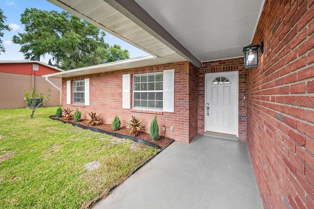 4905 Toni Ave, Lakeland, FL 33812 - view of exterior entry featuring brick siding and a yard