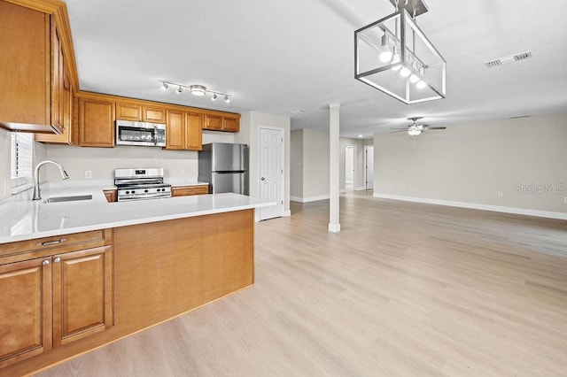 4905 Toni Ave, Lakeland, FL 33812 - kitchen featuring appliances with stainless steel finishes, brown cabinetry, light countertops, light wood-style flooring, and a peninsula