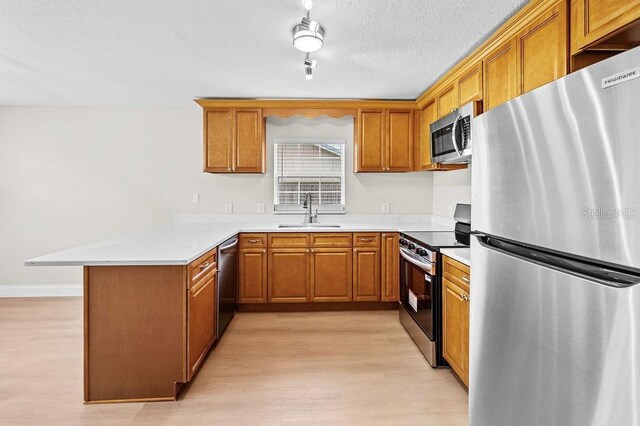 4905 Toni Ave, Lakeland, FL 33812 - kitchen featuring stainless steel appliances, a peninsula, light wood-style floors, brown cabinetry, and light countertops