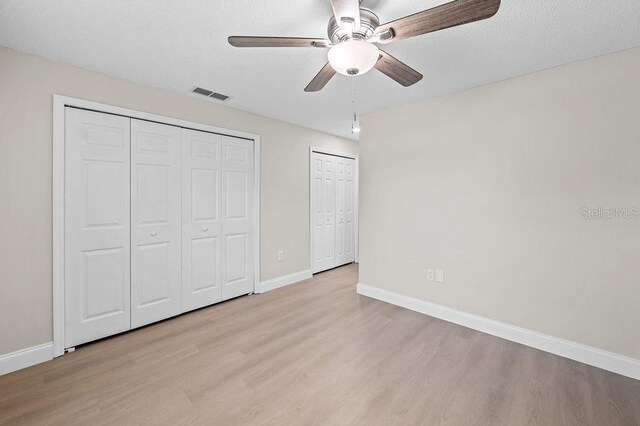 4905 Toni Ave, Lakeland, FL 33812 - unfurnished bedroom featuring wood finished floors, two closets, and ceiling fan