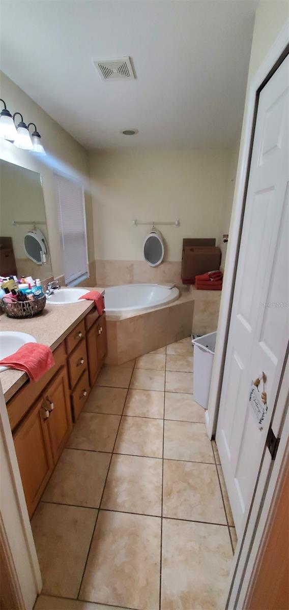 7689 N Galt Pt, Dunnellon, FL 34434 - bathroom featuring a bath, double vanity, and tile patterned floors