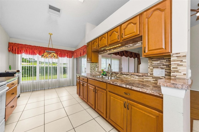 9519 Scenic Pine Ct, New Port Richey, FL 34655 - kitchen with vaulted ceiling, decorative backsplash, brown cabinets, light tile patterned floors, and hanging light fixtures