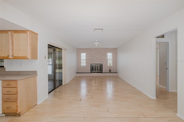 11127 Water Oak Dr, Port Richey, FL 34668 - unfurnished living room with a ceiling fan, light wood-style floors, and a fireplace