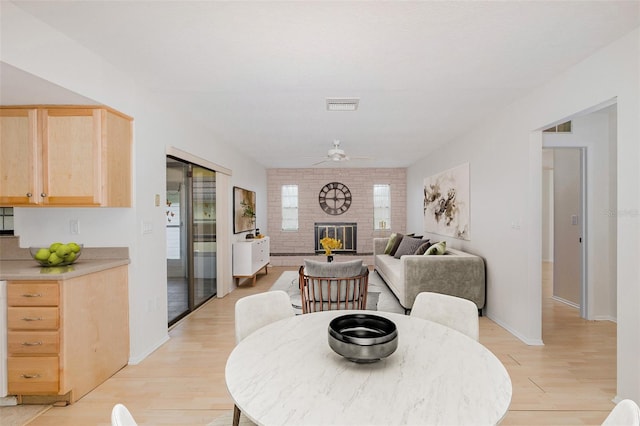 11127 Water Oak Dr, Port Richey, FL 34668 - dining room with light wood-style flooring, a ceiling fan, and a fireplace