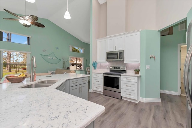 9626 Woodhollow Ct, New Port Richey, FL 34655 - kitchen with stainless steel appliances, high vaulted ceiling, a ceiling fan, white cabinetry, and decorative backsplash