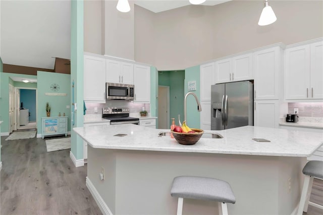 9626 Woodhollow Ct, New Port Richey, FL 34655 - kitchen featuring appliances with stainless steel finishes, high vaulted ceiling, white cabinets, backsplash, and a breakfast bar