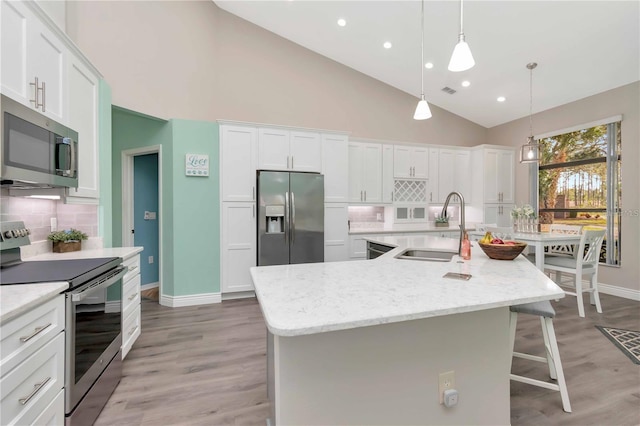 9626 Woodhollow Ct, New Port Richey, FL 34655 - kitchen with appliances with stainless steel finishes, a breakfast bar area, tasteful backsplash, white cabinets, and high vaulted ceiling