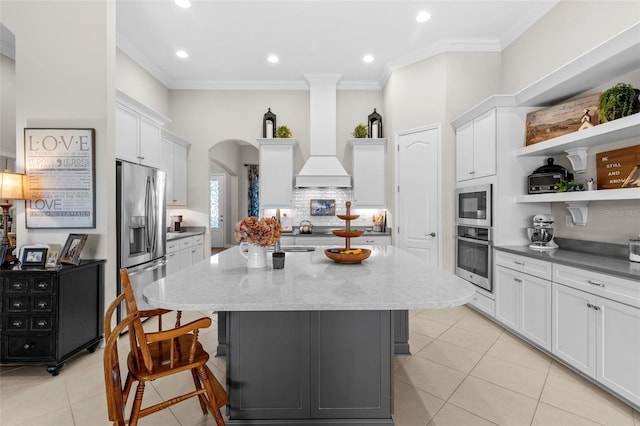 13208 Fawn Lily Dr, Riverview, FL 33579 - kitchen featuring stainless steel appliances, a kitchen island, light tile patterned flooring, crown molding, and white cabinets