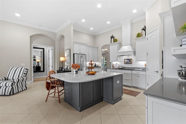 13208 Fawn Lily Dr, Riverview, FL 33579 - kitchen with stainless steel refrigerator, crown molding, custom exhaust hood, arched walkways, and backsplash