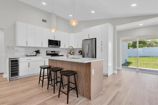 6529 Taylor Ct, New Port Richey, FL 34653 - kitchen with appliances with stainless steel finishes, beverage cooler, a breakfast bar area, decorative backsplash, and light countertops