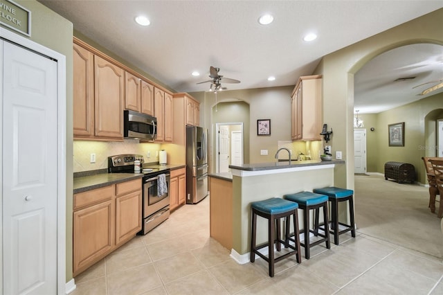 11126 Biddeford Pl, New Port Richey, FL 34654 - kitchen featuring appliances with stainless steel finishes, a ceiling fan, arched walkways, a kitchen breakfast bar, and dark countertops