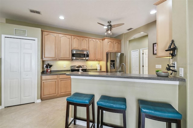 11126 Biddeford Pl, New Port Richey, FL 34654 - kitchen with appliances with stainless steel finishes, ceiling fan, a breakfast bar, dark countertops, and recessed lighting