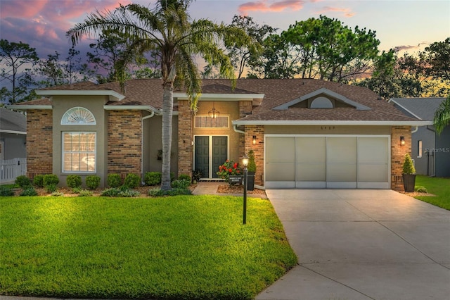 view of front of property with a lawn, concrete driveway, brick siding, and a garage