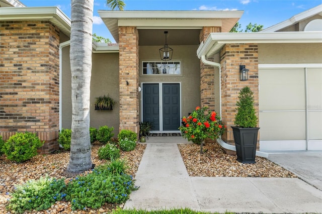 doorway to property featuring an attached garage and stucco siding