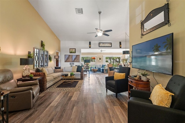living room with ceiling fan, wood finished floors, and a towering ceiling