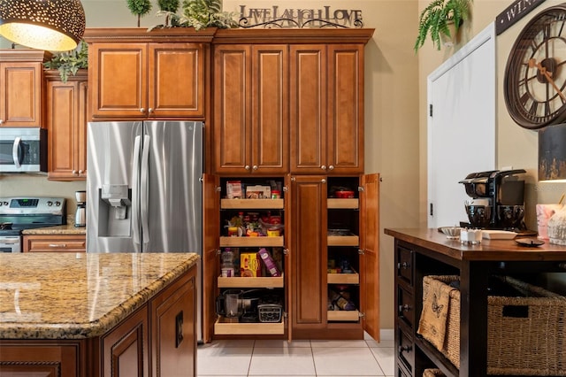 kitchen featuring appliances with stainless steel finishes, light stone countertops, light tile patterned flooring, and brown cabinets