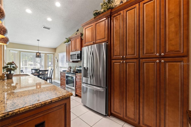 kitchen with appliances with stainless steel finishes, a textured ceiling, light tile patterned floors, light stone counters, and hanging light fixtures
