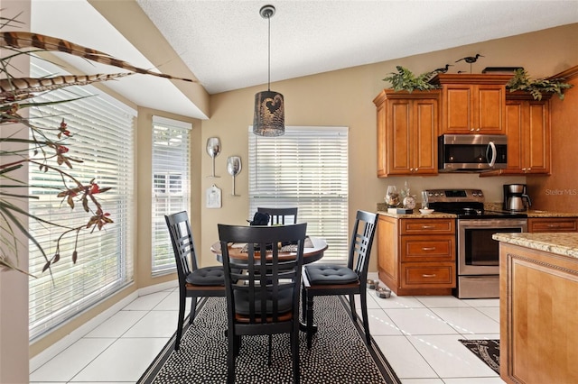 dining room with vaulted ceiling, plenty of natural light, and light tile patterned flooring
