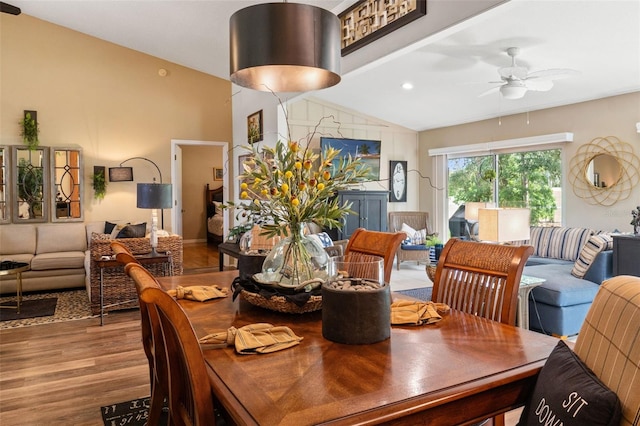 dining space with wood finished floors, a ceiling fan, and high vaulted ceiling