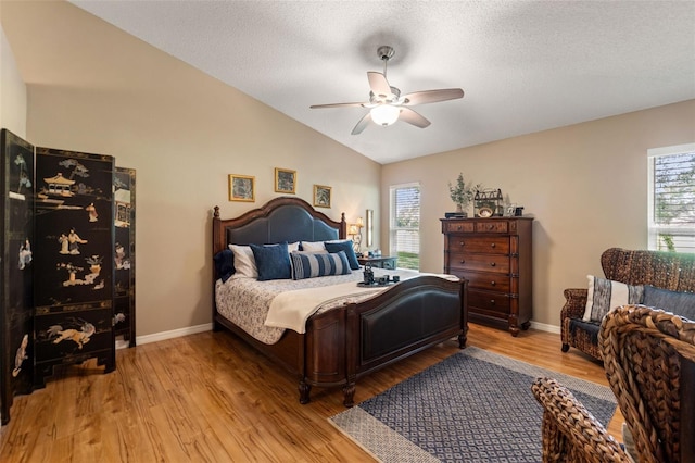 bedroom featuring vaulted ceiling, light wood finished floors, a ceiling fan, and a textured ceiling