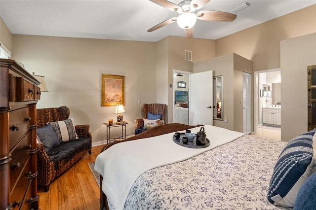 bedroom featuring light wood-type flooring, lofted ceiling, ensuite bath, and ceiling fan