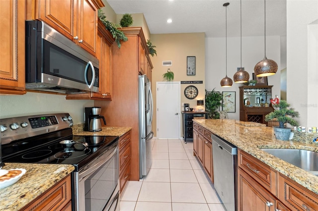 kitchen with stainless steel appliances, brown cabinetry, light tile patterned flooring, and light stone countertops