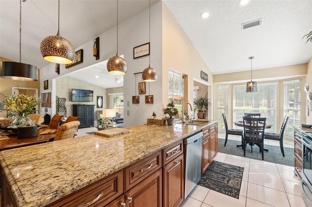 kitchen with lofted ceiling, appliances with stainless steel finishes, brown cabinetry, light stone counters, and healthy amount of natural light
