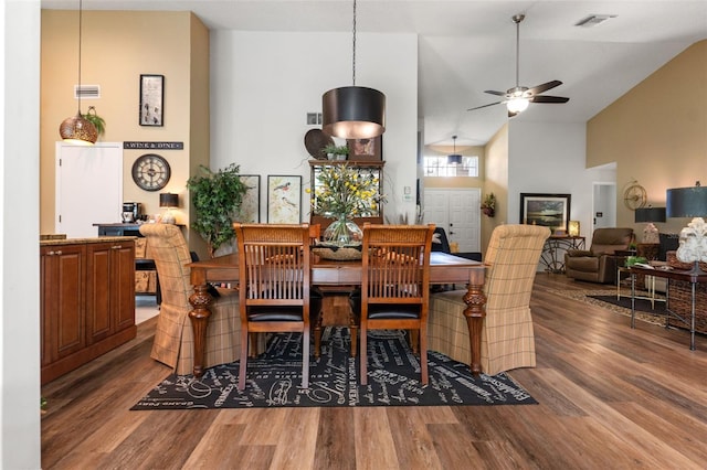 dining room with wood finished floors, a ceiling fan, and high vaulted ceiling
