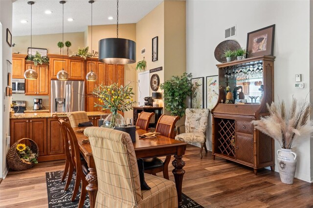 dining space featuring a high ceiling, light wood-type flooring, and recessed lighting