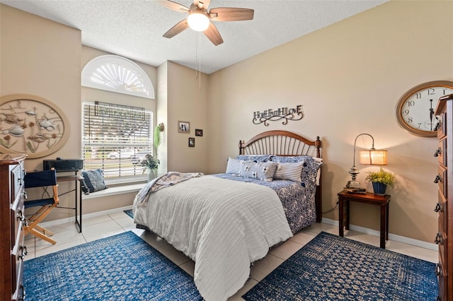 bedroom with a textured ceiling, light tile patterned floors, and a ceiling fan