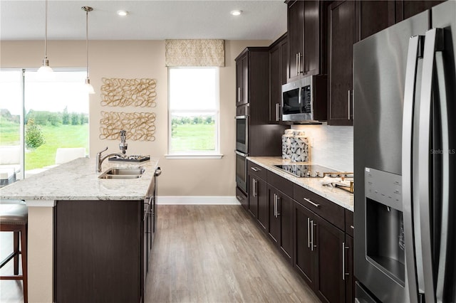 120 Venetian Palms Blvd, New Smyrna Beach, FL 32168 - kitchen with appliances with stainless steel finishes, a kitchen island with sink, wood finished floors, a kitchen bar, and light stone counters