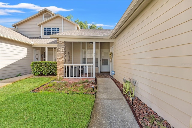 6519 Thicket Trl, New Port Richey, FL 34653 - doorway to property with covered porch, a shingled roof, and a yard