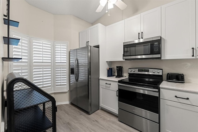 6519 Thicket Trl, New Port Richey, FL 34653 - kitchen with appliances with stainless steel finishes, light wood finished floors, light countertops, ceiling fan, and white cabinetry