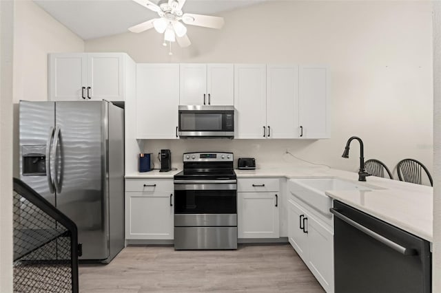 6519 Thicket Trl, New Port Richey, FL 34653 - kitchen with appliances with stainless steel finishes, vaulted ceiling, ceiling fan, light countertops, and white cabinets
