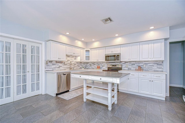 5523 Carlton Rd, New Port Richey, FL 34652 - kitchen with stainless steel appliances, tasteful backsplash, light countertops, white cabinetry, and recessed lighting