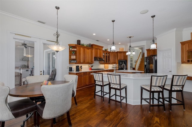 10508 Pontofino Cir, Trinity, FL 34655 - kitchen featuring black appliances, a center island with sink, brown cabinets, light countertops, and dark wood-type flooring